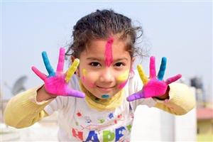Smiling child with paint on her hands and face.